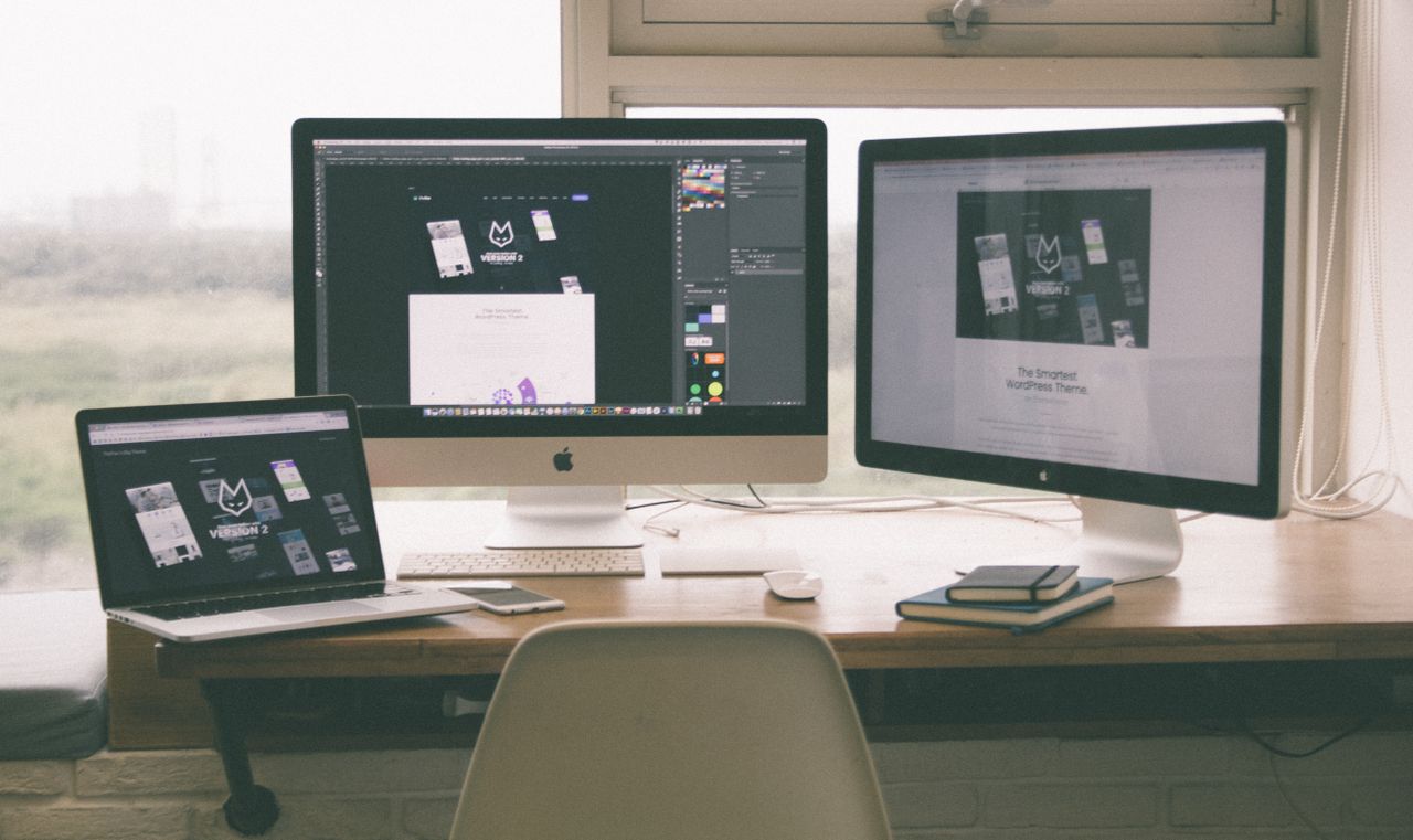 Espace de travail élégant et efficace avec plusieurs écrans, un ordinateur portable et un smartphone, mettant en avant un projet de web design.
